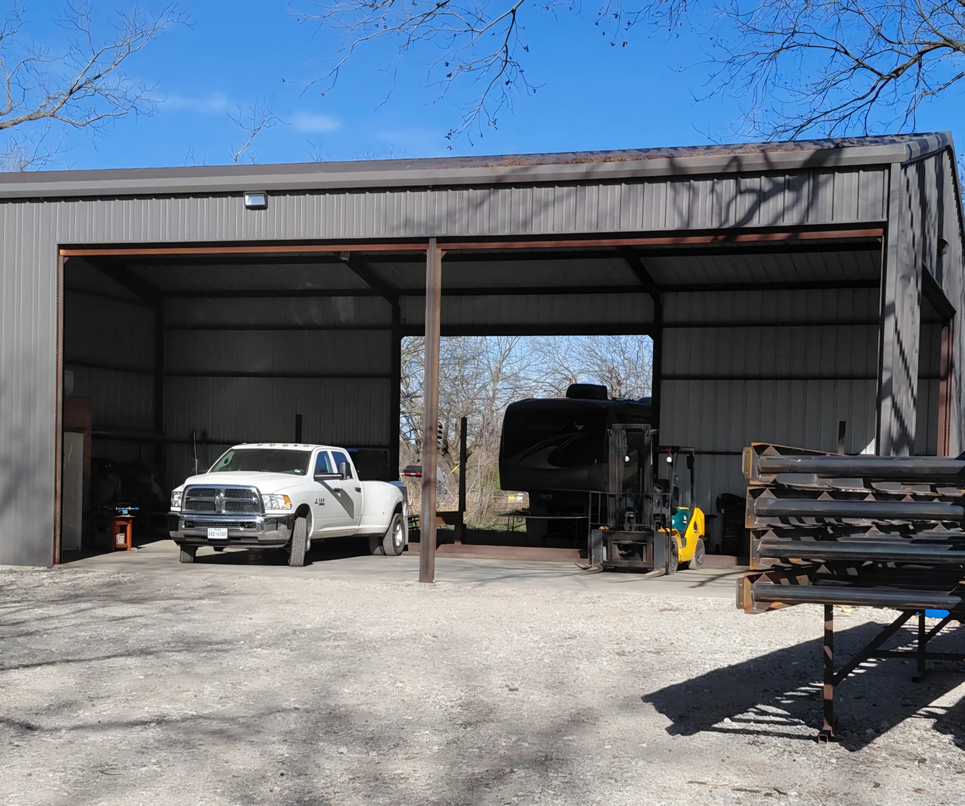 Shop floor with truck, trailer, and steel stock racked and ready